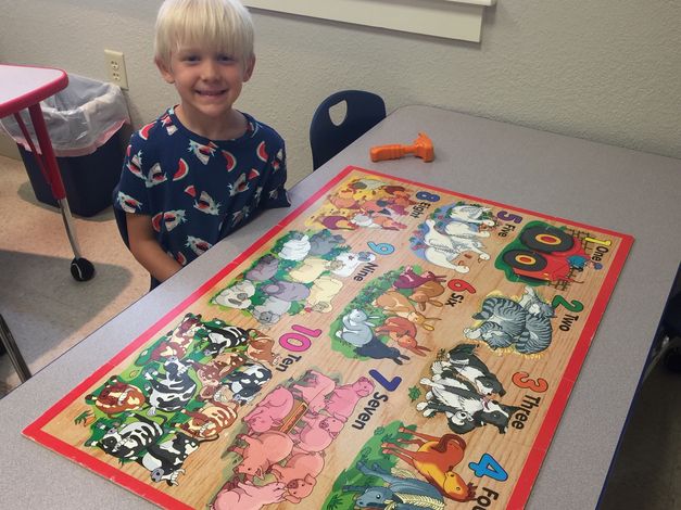 Kindergartenboypracticeshisnumberswhileputtingtogetherapuzzle Elementary School at Haywood Christian Academy